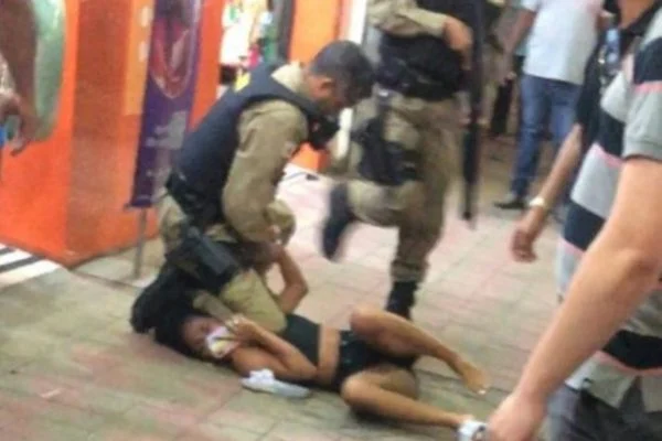 PMs abordam mulher com criança no colo, a imobilizam no chão e pessoas se revoltam, assista